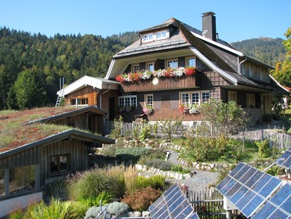 Naturhotel - Haus Sonne im Sommer, im Vordergrund der Kräutergarten und Solarpanels. - Haus Sonne - das vegetarische Bio-Hotel